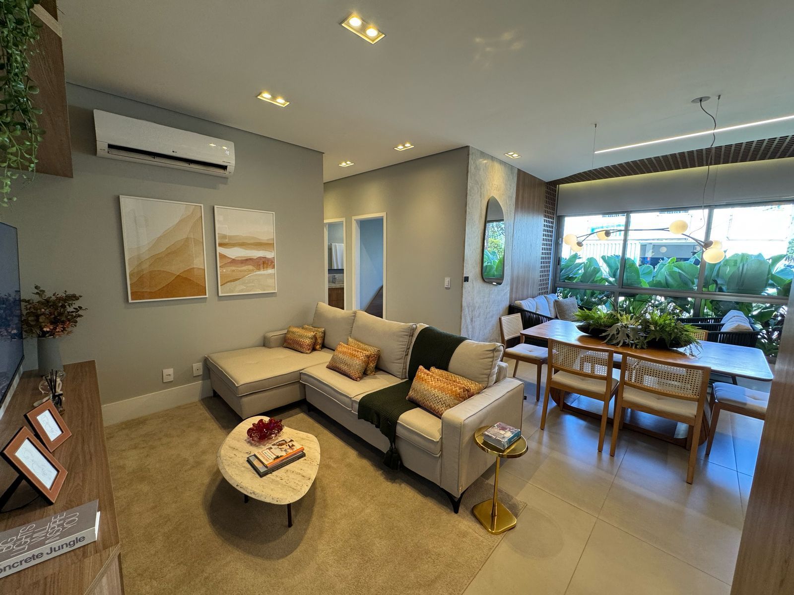 Living do apartamento decorado do Espaço Conceição com sofá em L, mesa de jantar ao fundo e ar-condicionado split na parede