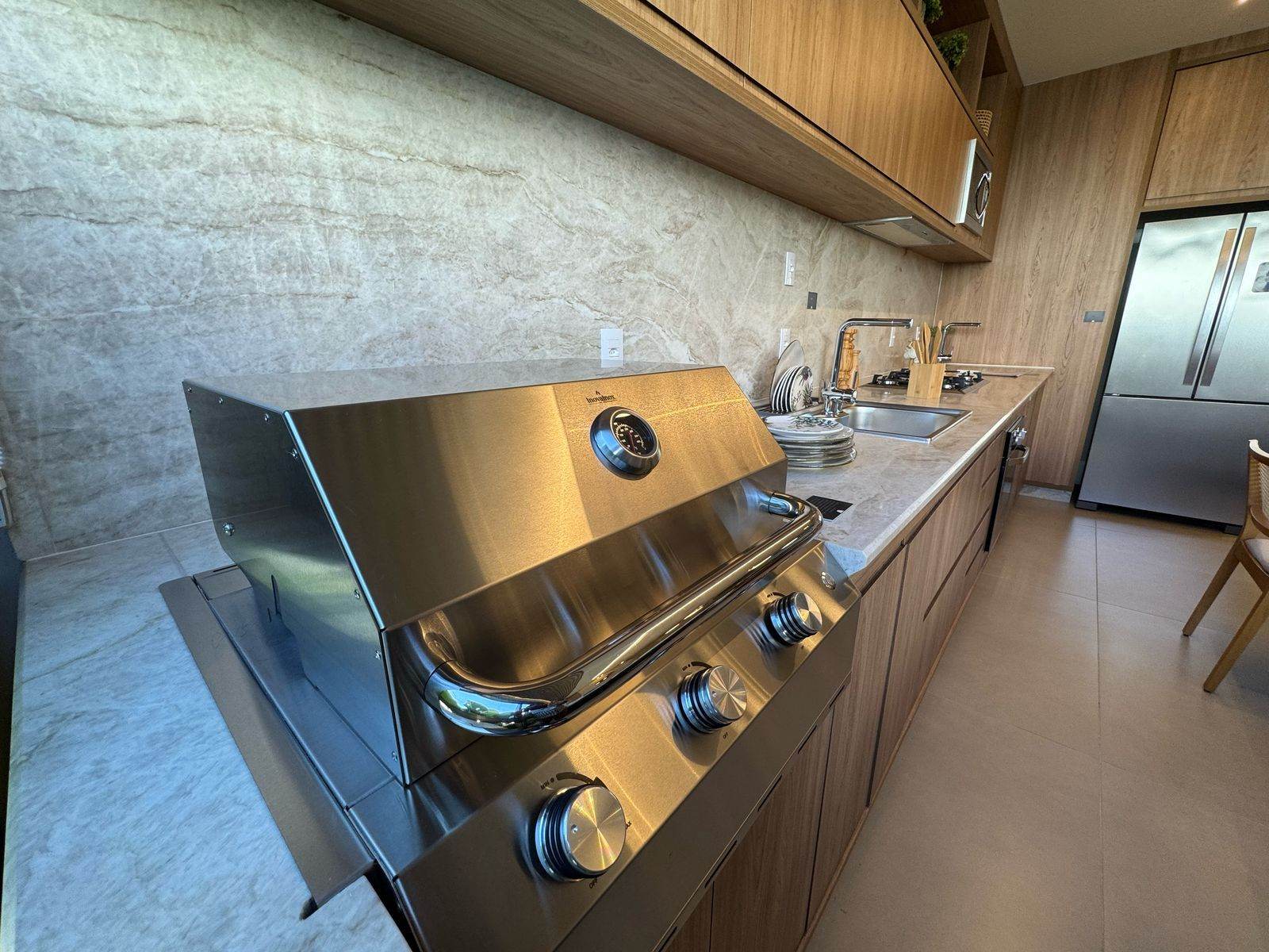 Churrasqueira a gás de embutir na bancada da varanda gourmet do apartamento decorado